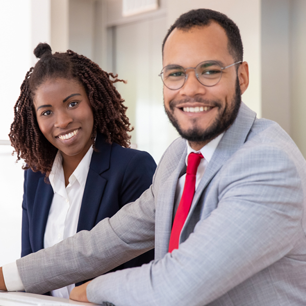 Cheerful business people using desktop computer. Young African American business people working with computer and smiling at camera in office. Business and technology concept